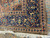 Folded corner detail revealing navy border rosettes, ivory fringe and short antique wool pile