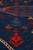 Raised Sumak brocade texture in close focus with scarlet tree of life motifs on indigo