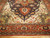 Close angle of ivory spandrels, green leaf motifs and rust border on Indian Serapi wool rug