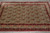 Overhead detail of the ivory field showing repeating paisley rows framed by deep red floral borders
