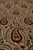Macro close-up of hand-knotted wool pile showing feathered paisley outlines in green, crimson and dark brown