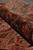 Rolled edge showing lustrous wool pile, paisley border drawing and rich rust and green tones