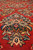 Macro of hand-knotted wool pile showing rose rosettes and navy leaf work on antique red