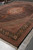 11'6" x 16'6" Tabriz rug photographed lengthwise on showroom floor, black field and rust medallion