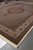Vertical full length view of oversize Persian rug with ivory ground and brown medallion field