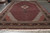Angled full length view of red and black oversize Herati fish pattern rug with cotton fringe