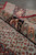 Rolled corner showing plush wool and silk pile depth beside the black palmette border vine