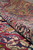 Folded pile reveals soft wool nap, crimson tones and indigo blue floral detail of the field