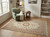 Ivory Isfahan rug styled in a sunlit reading room beside a green velvet armchair and bookshelves
