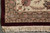 Corner detail of ivory flower border, burgundy outer band and hand-tied cotton fringe