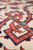 Macro of wool pile showing red interlaced diamond knot outlined in navy with gold accents