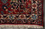 Corner of the crimson border with navy cartouche, ivory guard band and hand-tied wool fringe