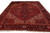 Wide floor shot of the red Persian village rug with dark navy border and cream fringe