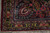 Corner detail with navy border, rose rosettes and burgundy selvage on this antique Sarouk