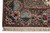 Corner view with the woven signature cartouche in the end border beside cream fringe