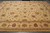 Angled floor view of oversize hand-knotted wool rug showing ivory ground and mauve border bands