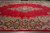 Crimson open field and navy floral border of this hand-knotted wool Kerman rug seen from above