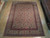 Large 9'1" x 12'5" Isfahan wool rug laid on light hardwood showroom floor