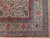 Corner detail of multi-band red and blue borders framing the beige paisley field and fringe