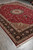 10' x 13'8" red Tabriz rug laid flat on grey tile, diagonal full view