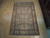 6'9 x 11 Nain rug laid on light hardwood showroom floor beside a red Persian rug