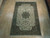 6'7" x 9'11" Persian Tabriz rug laid flat on light wood showroom floor