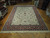 Traditional ivory and red hand-knotted wool rug displayed on parquet floor in our showroom
