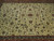 Close-up of ivory field with green palmettes, rosettes and scrolling floral vine motifs
