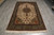 Overhead shot of 6x10 hand-knotted Persian rug on grey floor showing all-over vine field
