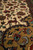 Woven deer and hunting bird motifs beside the camel colored spandrel of this Tabriz