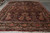Angled floor view of antique Persian rug with black border, rose sprays and ivory cotton fringe