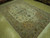 Angled showroom view showing sage green border and ivory field of this 7x10 Tabriz rug