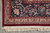 Corner detail of navy main border, beige guard band and hand-knotted cotton fringe on grey floor
