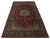 9'7" x 16'3" Persian Najafabad rug photographed at an angle showing deep red field and navy border