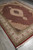 Diagonal view showing the ruby red field, cream fringe and multi-band border of this wool and silk rug
