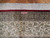 Woven signature cartouche in the ivory border above the white silk fringe end