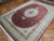 Angled view showing silk sheen, ivory floral border and sage green guard stripes on hand-knotted rug