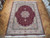9'9" x 13' Tabriz rug displayed on parquet floor showing burgundy field and ivory border