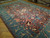 Angled view showing teal green border and plum field of this large hand-knotted Pakistani Oushak rug