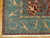 Corner detail with ivory fringe, teal border scrollwork and rust outlines on natural hand-spun wool pile