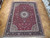 9'8" x 12'10" Persian Tabriz rug laid on parquet floor showing full burgundy field