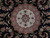 Close-up of ivory and rose center medallion surrounded by paisley and flowering vines on black