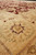 Beige border corner detail with green leaf spray and maroon outlines seen at floor level