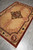 6 x 9 silk rug angled on grey tile showing carved pink fret and medallion