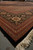 Angled corner of oversize Persian Tabriz rug showing black main border and thick fringe