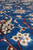Macro detail of wool and silk pile with red vine scrolls over deep blue ground