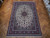 8'3" x 12'4" Persian Isfahan rug laid on herringbone parquet floor showing full ivory field