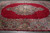 Ruby red Kerman rug on warehouse floor showing ivory medallion and deep navy floral border