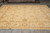 13'8" x 13'11" square wool rug displayed in warehouse showroom with rolled Oriental rugs behind