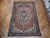 Rust and indigo Serapi area rug laid on herringbone parquet floor in natural daylight